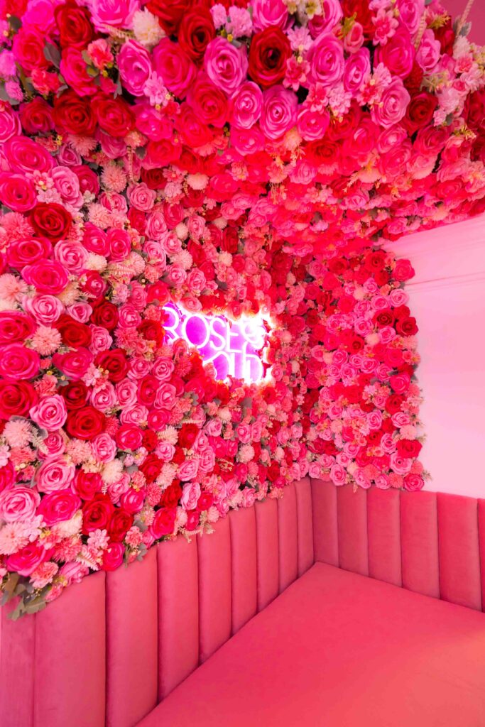 Charming exterior shot of Rose Oud Café with evening lights and floral entrance